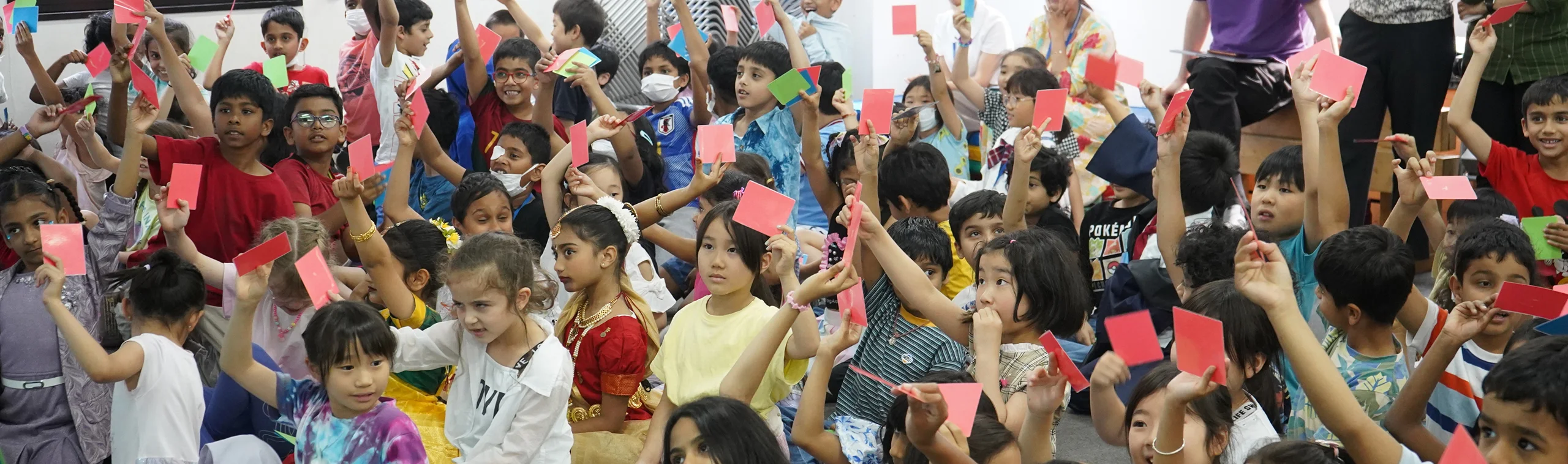Children holding up colorful cards in a lively classroom activity.