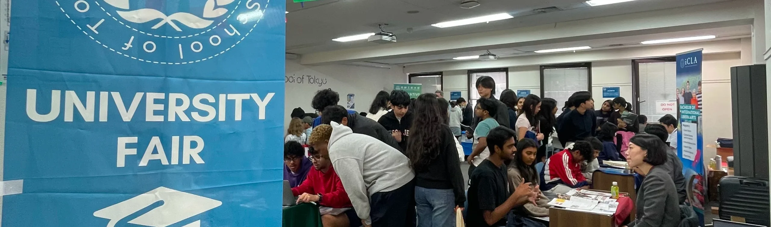 Students attending a busy university fair with informational booths and engaging representatives.