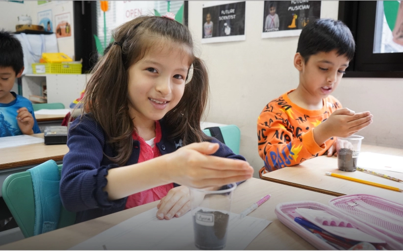 Children engaging in a classroom science experiment with soil samples, smiling and focused.