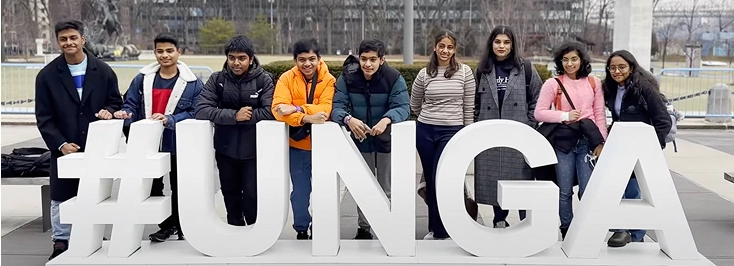 Group of young people posing with #UNGA sign outdoors.