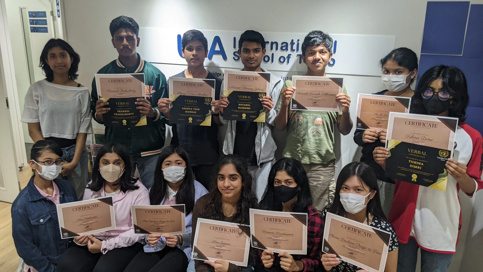 Group of students proudly holding certificates at an award ceremony, showcasing their achievements and smile.