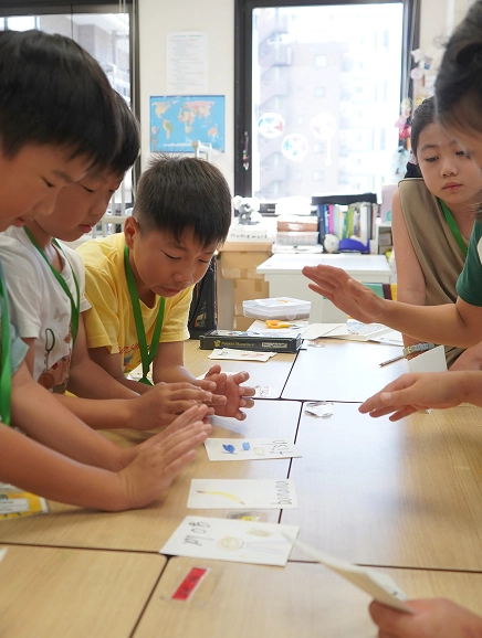 Children engaged in a classroom activity, collaborating on a creative project with guidance from a teacher.