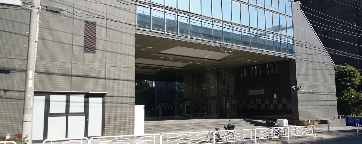 Modern office building exterior with glass facade and open entryway on a sunny day.