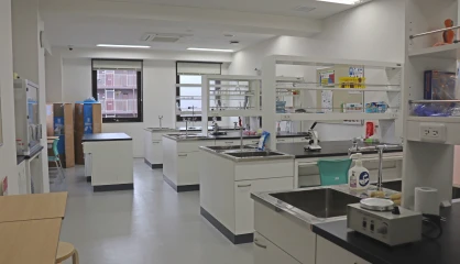 Modern laboratory interior with workstations, scientific equipment, and ample natural light through large windows.