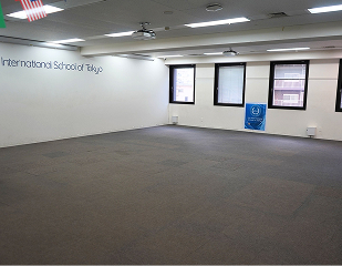 Empty classroom in Tokyo international school with white walls and large windows, ready for setup.