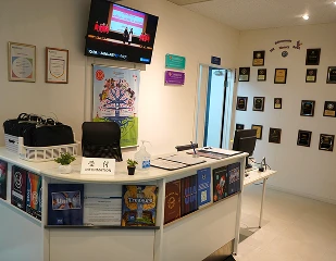 Modern reception area with awards on the wall, a TV screen, and informational brochures on the desk.